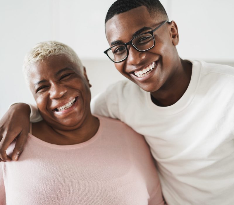 Older black woman embracing young black boy in glasses smiling